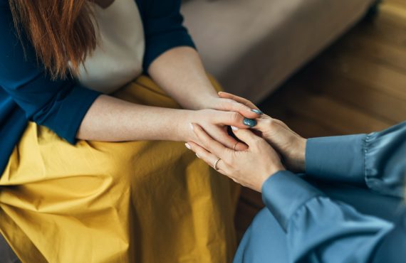 Two women sitting in armchairs and talking. Woman psychologist talking to patient Two women sitting in armchairs and talking. Woman psychologist talking to patient woman. Coach giving hands to smiling woman. Therapist's gestures. Female talking in coworking office